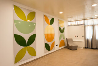 3 colourful enamel panels mounted on the wall, vibrant greens and oranges