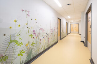 Delicate but colourful biophilic wall vinyl on the wall of a corridor including ferns, long grasses, foxgloves