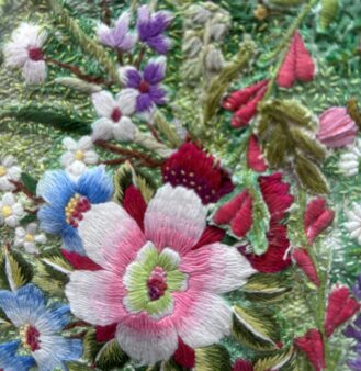Hand embroidered pink, blue and purple flowers on a green background