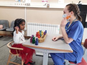 A child with headphones on and interacting with a nurse