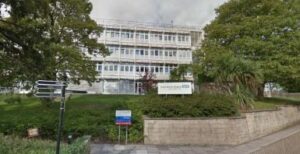 An image of the front of Yeovil Hospital. The image shows the trusts logo. The building is a art deco 80 design.