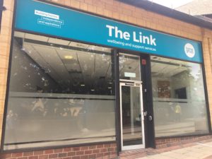 An image of a shop front with a blue sign above the shop front with the words 