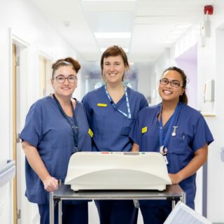 Image of three NHS colleagues smiling in front of the camera.