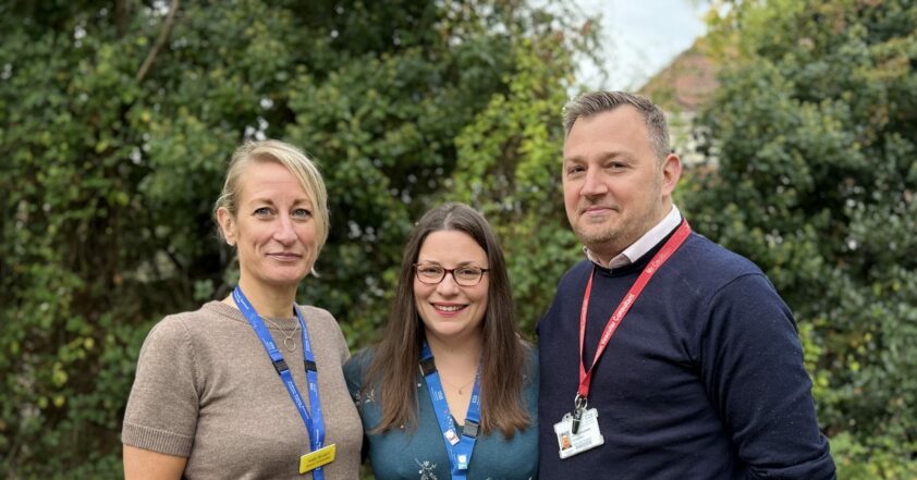 Sally Brant, Leanne Ashmead and James Coulston stood in a line outside with grass and a green bush behind them