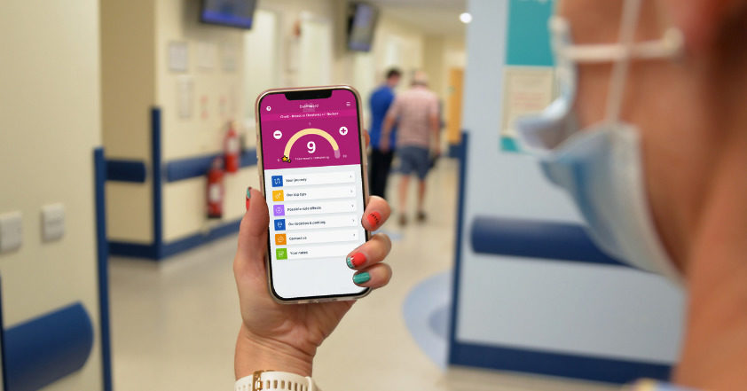 A picture of a women holding a smartphone with the Beacon Buddy app showing on the phone.