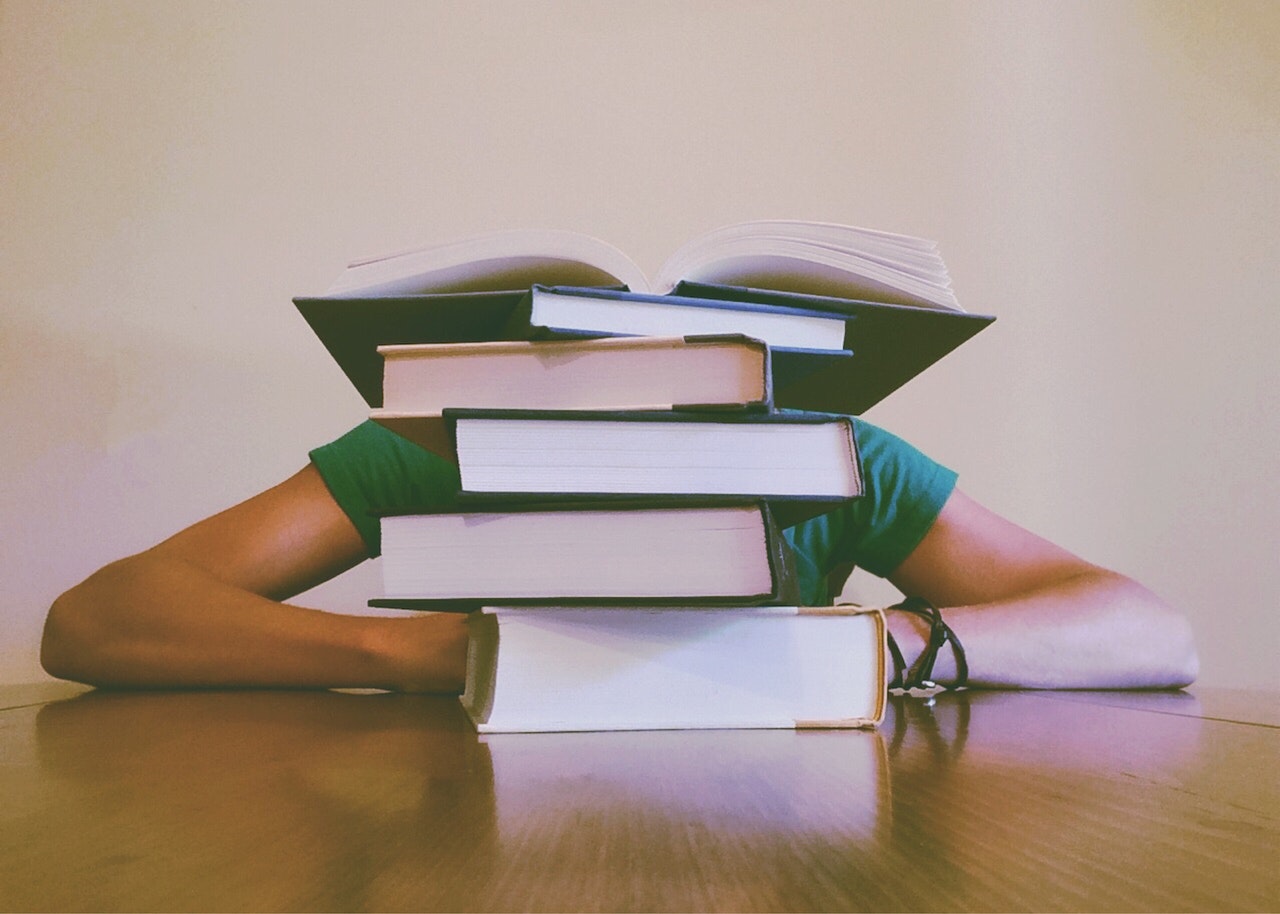 Person Slouched Behind Books