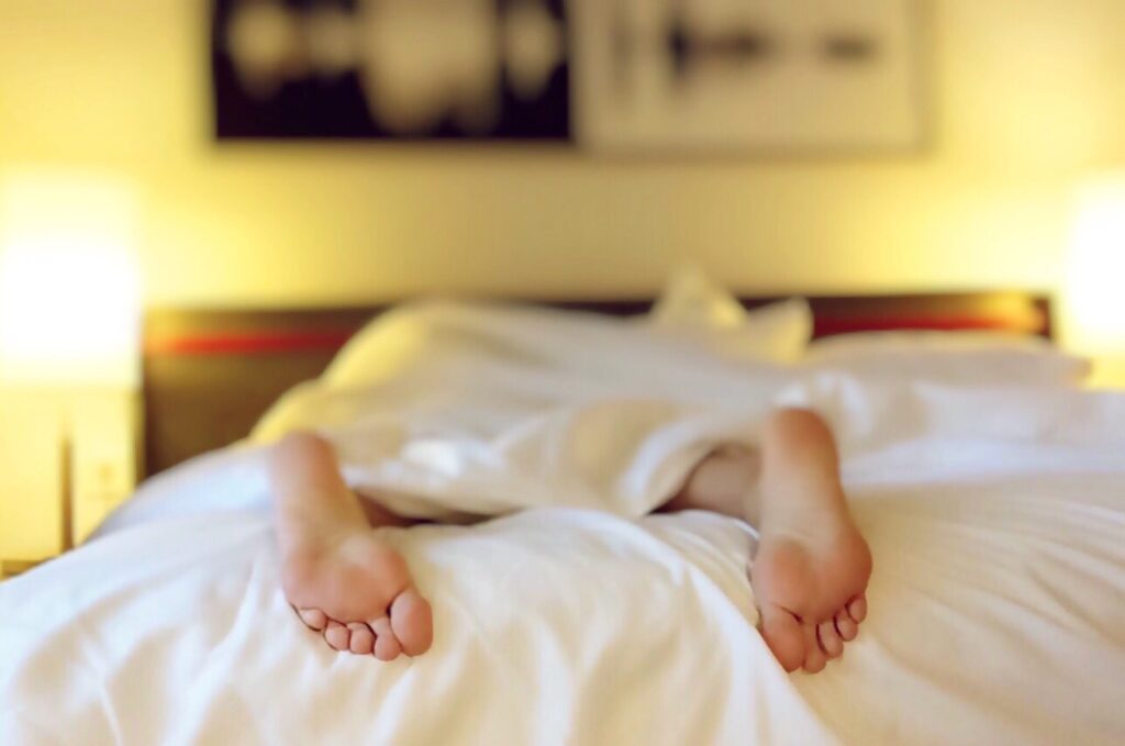 a persons feet sticking out the bottom of a bed