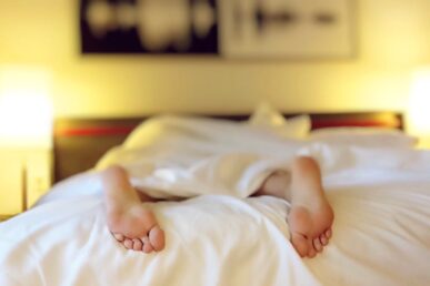 a persons feet sticking out the bottom of a bed