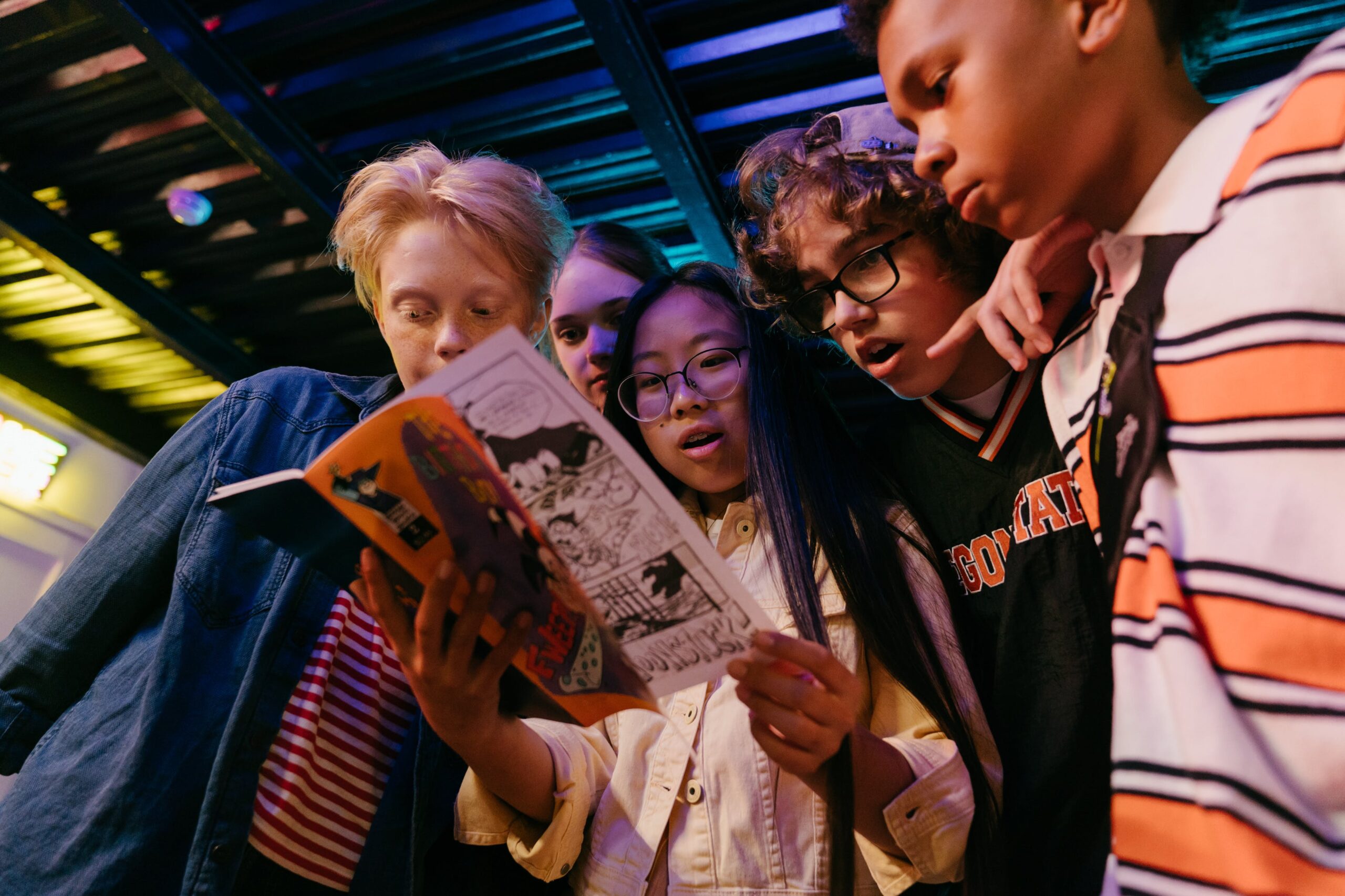 a group of five teenagers reading a magazine