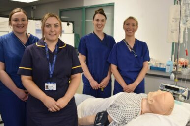 A photo of four operating department practitioners standing next to a simulation doll at Musgrove Park Hospital.
