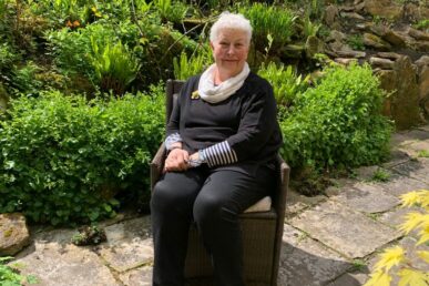 A photo of former chaplain Linda Hann sat in a garden.