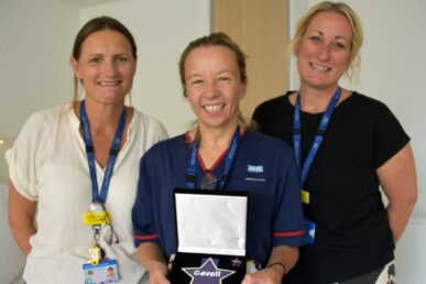 A photo of midwife Pip Quinn stood with two other maternity leads. Pip is holding an awards plaque.