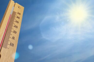 A photo of a thermometer and a sunny blue sky.