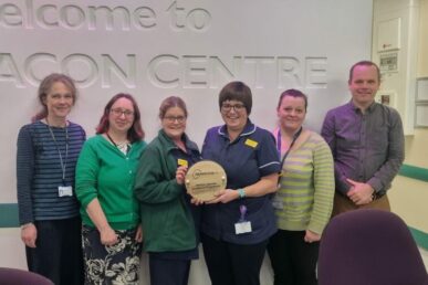 A group of six people holding an awards plaque for cancer care.