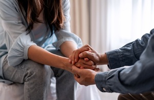 A photo of a woman being comforted by someone holding their hands.
