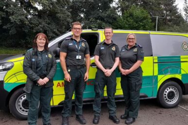 Four people in ambulance paramedic uniforms stood next to a mental health response vehicle.