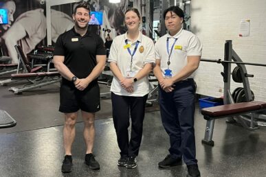 Two physiotherapists and a gym worker standing in a gym environment.