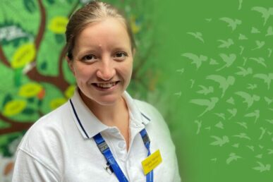 A photo of neonatal physiotherapist Hayley Harrison stood in the Musgrove Park Hospital children's unit, with a mural of a tree on the wall behind her.