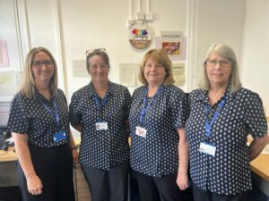 Four colleagues from Somerset's audiology administration team stood in an office at Wellington Hospital.