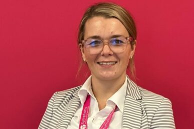 A photo of nurse leader for Symphony Healthcare Services, Kate Williams, who is stood against a red background