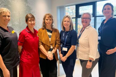 Six colleagues involved in breast care are stood in the reception area of the Maple Unit breast cancer unit at Yeovil Hospital.