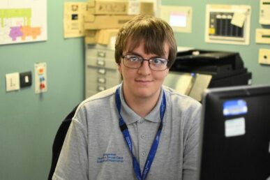 A photo of supported intern Matthew Lloyd sat in an office at Bridgwater Hospital.