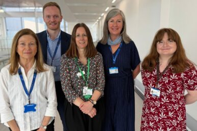 A photo of five cancer support workers stood in a corridor.