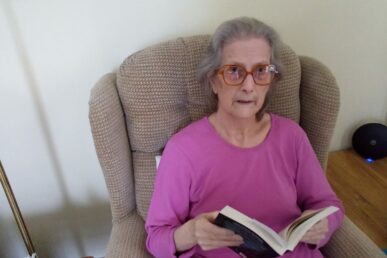 A photo of a person called Ivy sat on a chair in her home.