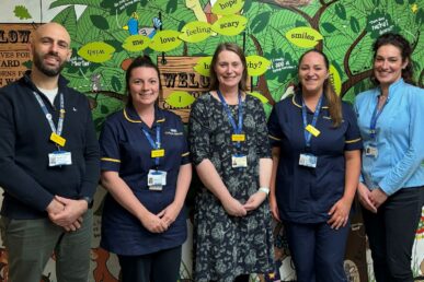 A photo of five colleagues in the paediatric department at Musgrove Park Hospital, stood next to a mural on the children's unit.
