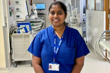 A photo of a Sandhya Puli - a nurse at Yeovil Hospital - stood in front of an operating theatre,