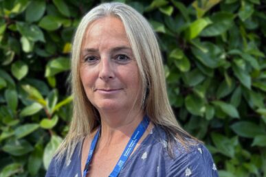 A photo of Home Treatment Team manager Carolyn Broom stood next to green bushes.