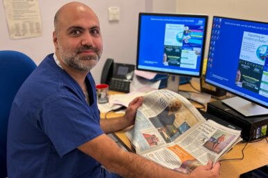 A photo of consultant cardiologist, Dr Mo Sahebjalal, sat next to a computer in a cardiology reporting room.