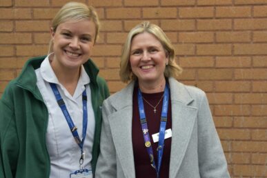 A photo of two speech and language therapists stood in front of a brick wall.