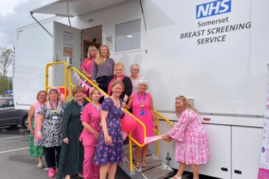 A photo of a group of colleagues from our breast screening service dressed in pink, stood next to our new breast screening unit.