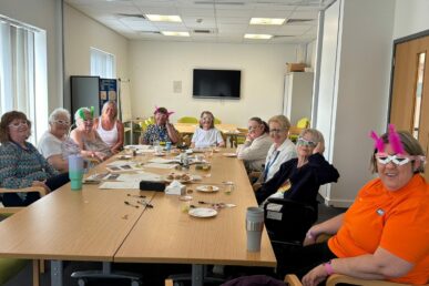 A photo of a group of patients and colleagues at Bridgwater Hospital sat in a room for a memory cafe. The people all have funny looking glasses as part of a Eurovision special edition of the day.