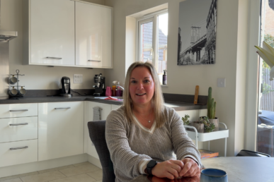 A photo of patient Claire Green sat in her kitchen,
