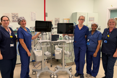 A photo of five colleagues in theatre scrubs within an anaesthetic room, with stood with specialist airway equipment.