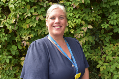 A photo of new lead bereavement key worker for child death Emma Thornhill stood in front of greenery.
